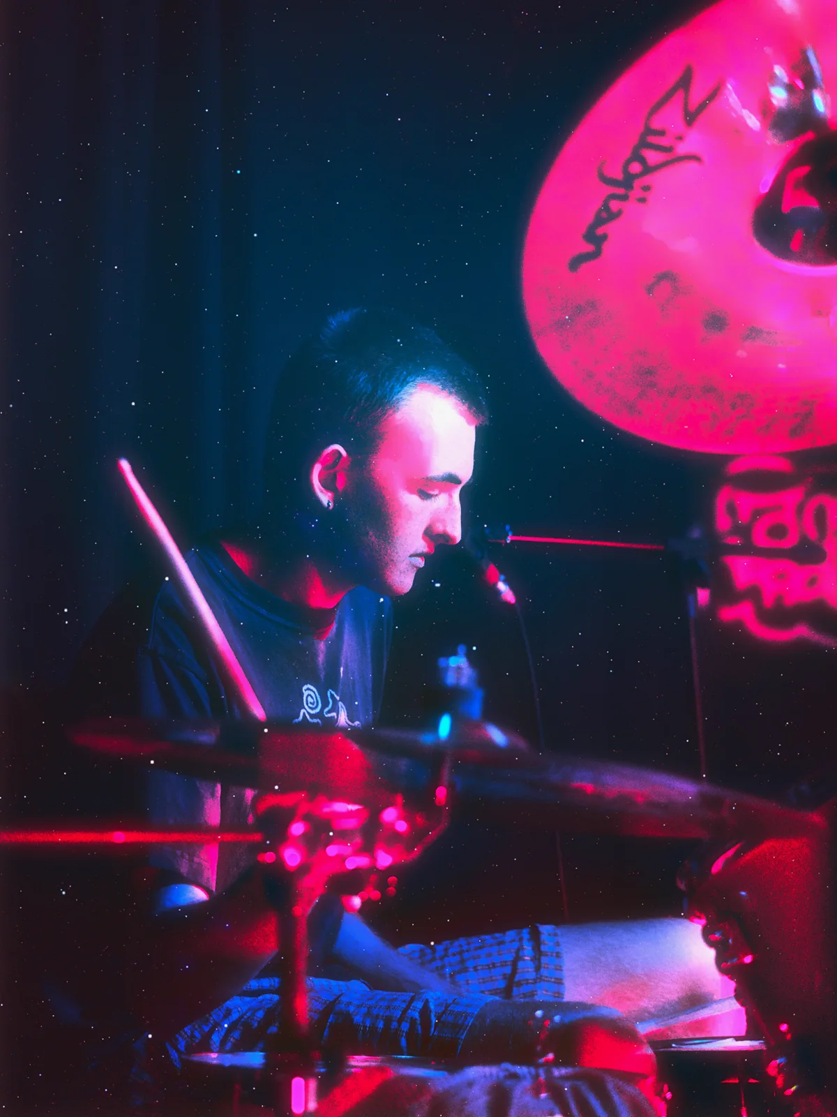 Chestr drummer under magenta and blue stage lighting