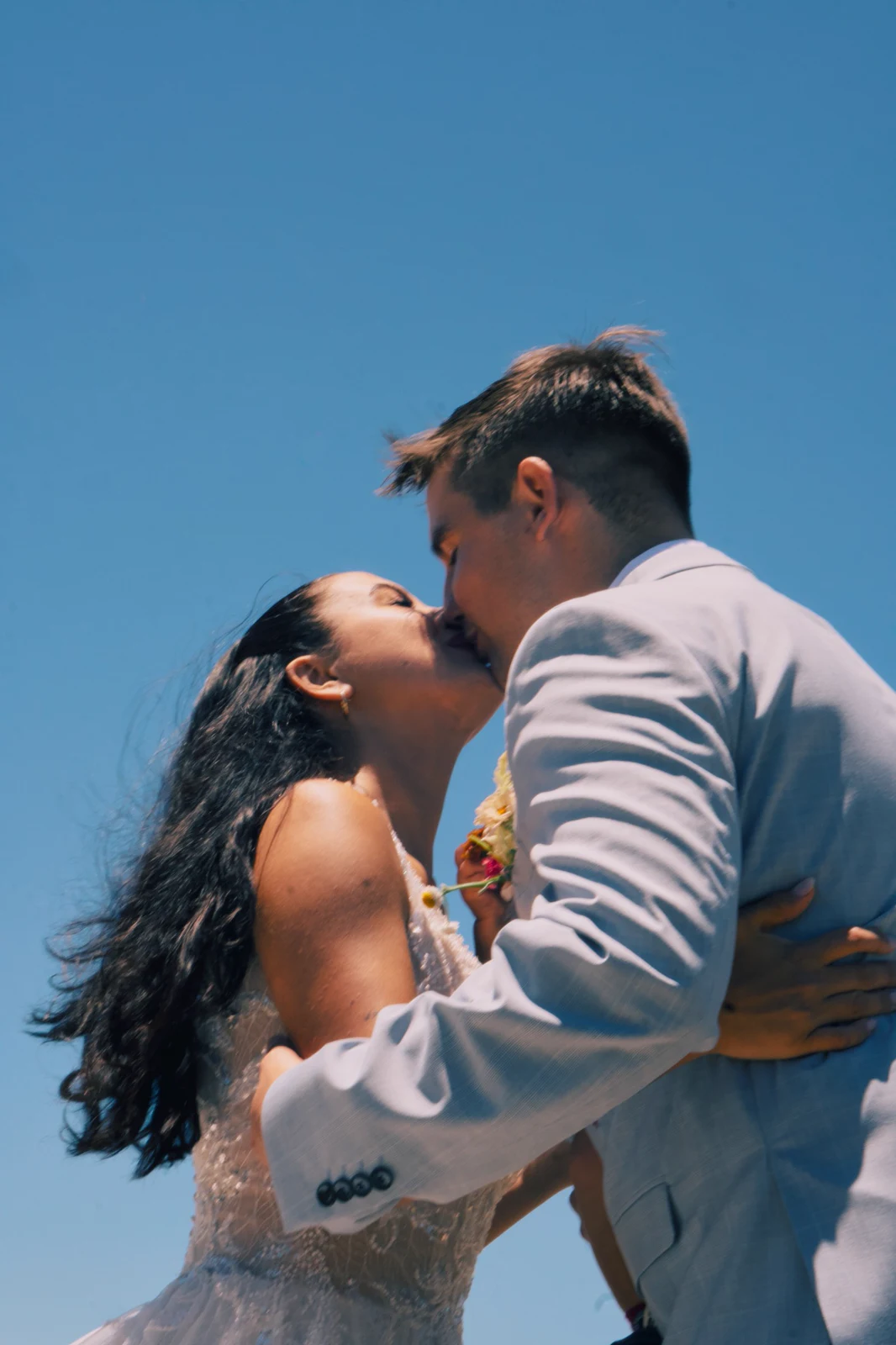 The couple kissing beneath a blue sky