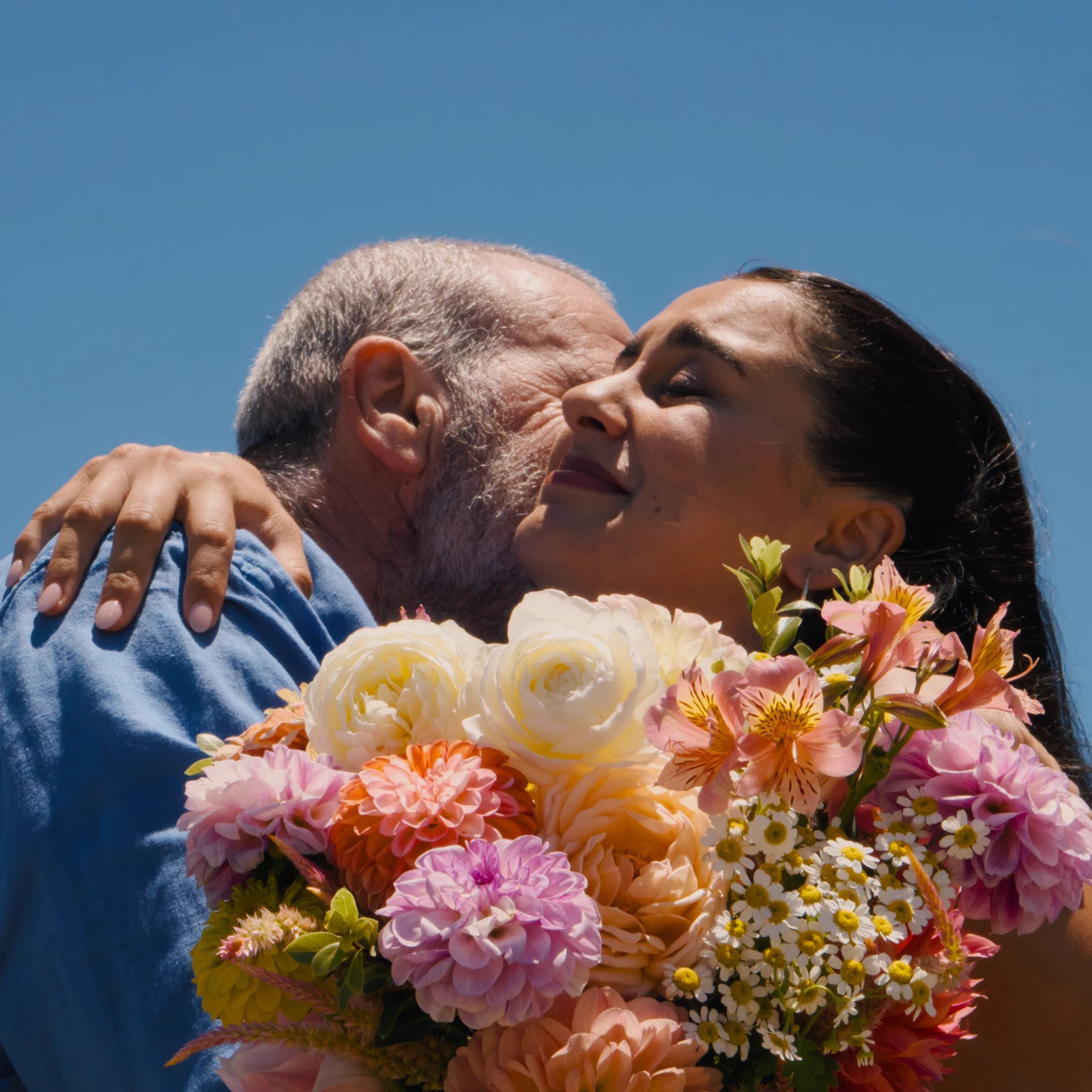 The bride embracing a guest with her bouquet in the foreground